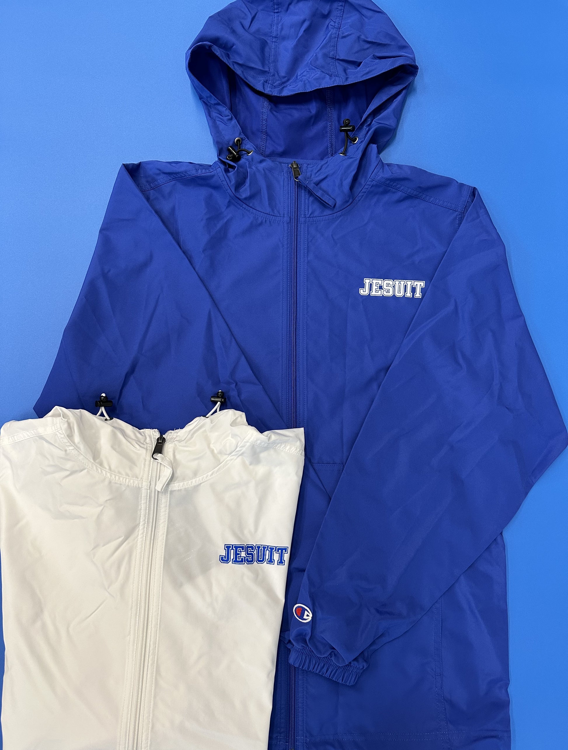 Champion.  100% polyester micro poplin fabric with water resistant coating.  Open bottom with shock cords.  Scuba collar with hood including shock cords.  Lower front on-seam pockets.  Elasticated cuff to block wind.