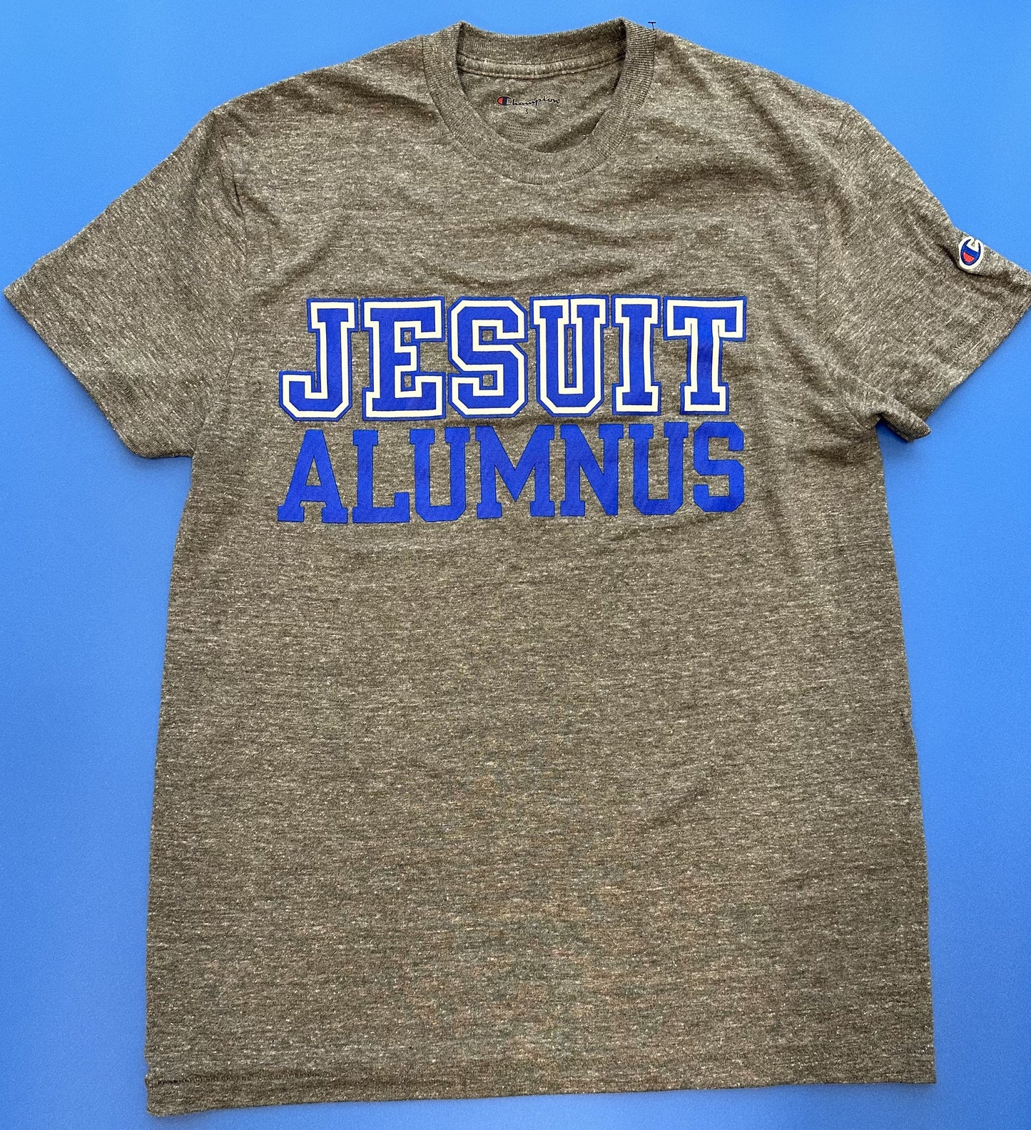 Champion. 50% Polyester/37% Cotton/13% Rayon Jersey. 1 x 1 rib at collar. Set in short sleeve with slightly shorter, more modern fit. Jesuit Alumnus logo.
*Visit the Shop at Carrollton & Banks for more styles.