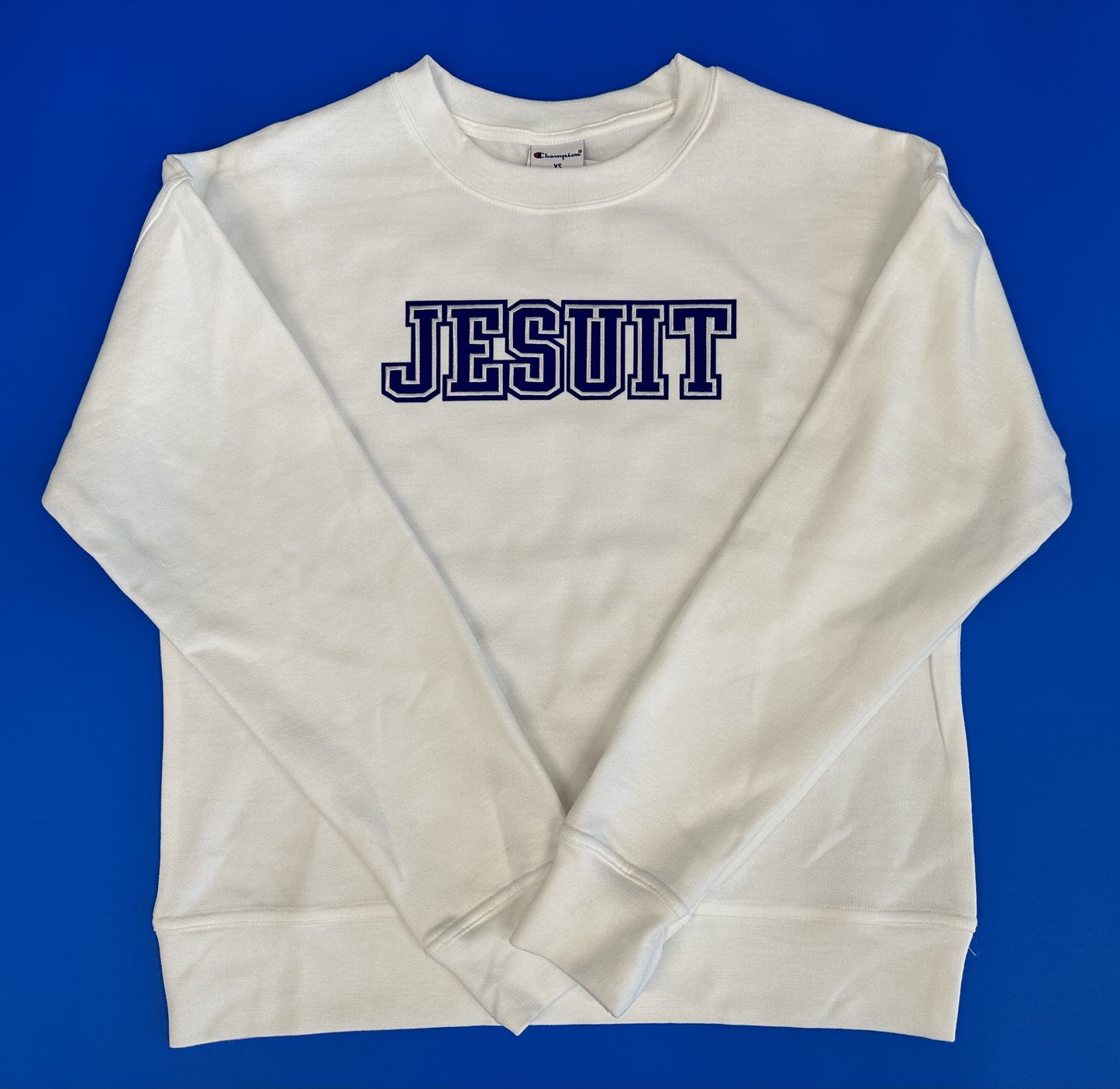 Champion. 50% Cotton/50% Polyester. Rib collar, cuff, waistband. Relaxed fit and modern length. JESUIT logo.