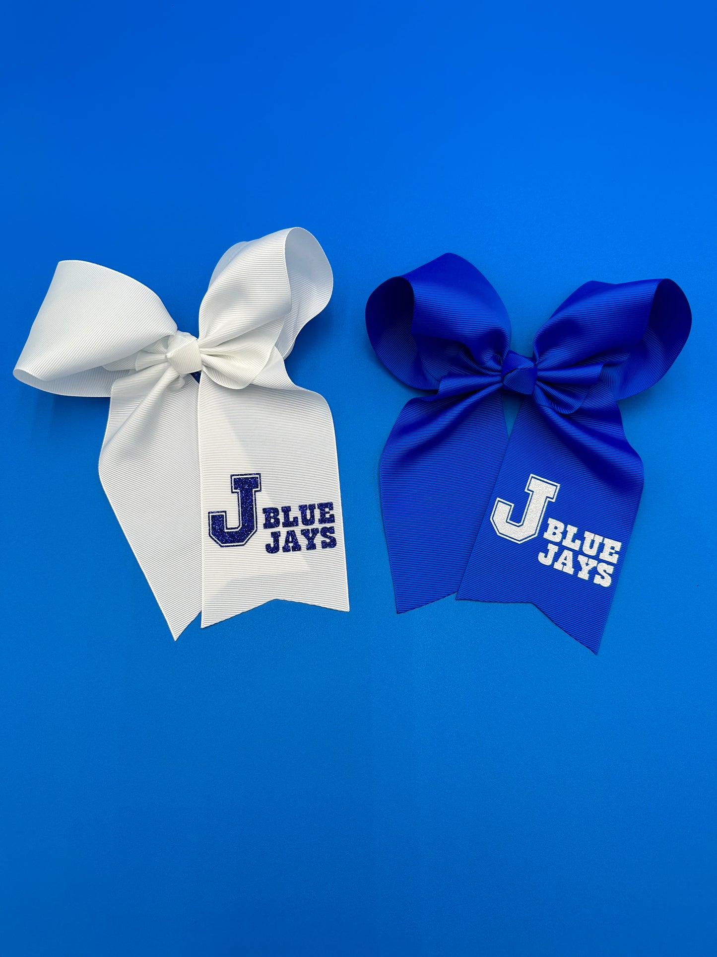 Cheer style large bows. Made with 3 inch ribbon in two colors! 6 to 7" drop. Alligator clip to hold in place.