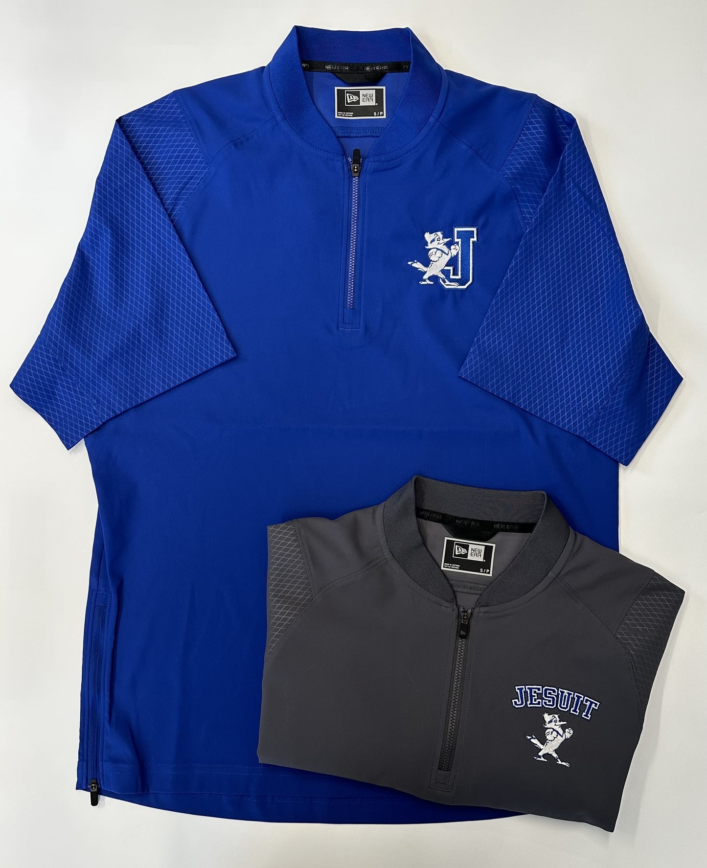 New Era. 94% polyester/6% spandex with durable water-repellent (DWR) finish. Rib-knit neck with locker loop. Raglan sleeves embossed with subtle Diamond Era pattern. Vislon® zipper with easy-grip, textured New Era zipper pull. Right side seam zipper for easy on/off. Drop tail hem. J/Jayson logo on Royal Blue. Jesuit with Jayson logo on Graphite.