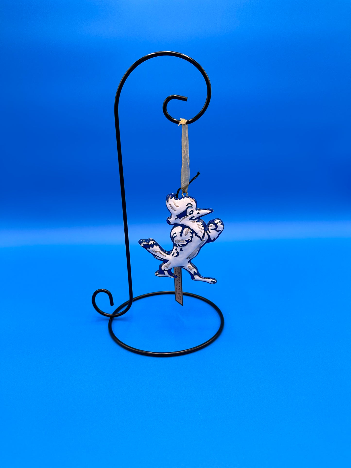 Kitty Keller Designs. Display your keepsake Jesuit ornaments year round with this all season display! Single Hanger ornament display stand. Smooth Wire construction with glossy black finish. Stand is 11-1/2"H & holds items up to 8"L x 5" diameter. Base is 5-3/8" diameter. Ornament sold separately!