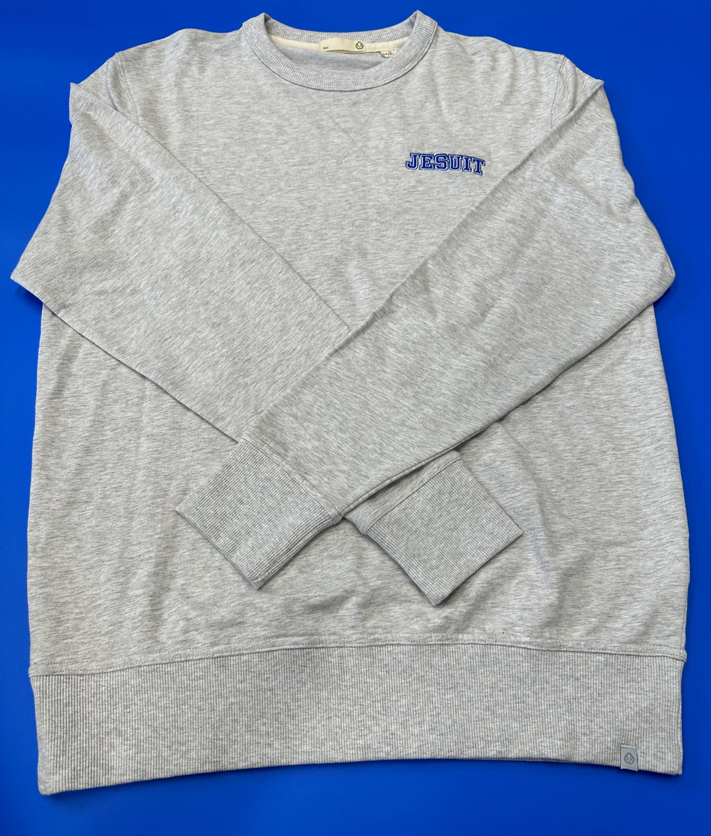 Tasc Performance. 53% Organic Cotton/43% Viscose from bamboo/4% Lycra. Cross-over stitch detail at front neck. 2 x 2 rib collar, sleeve cuffs, and bottom band, tapered to bottom opening. 28.5" body length. Embroidered JESUIT logo.