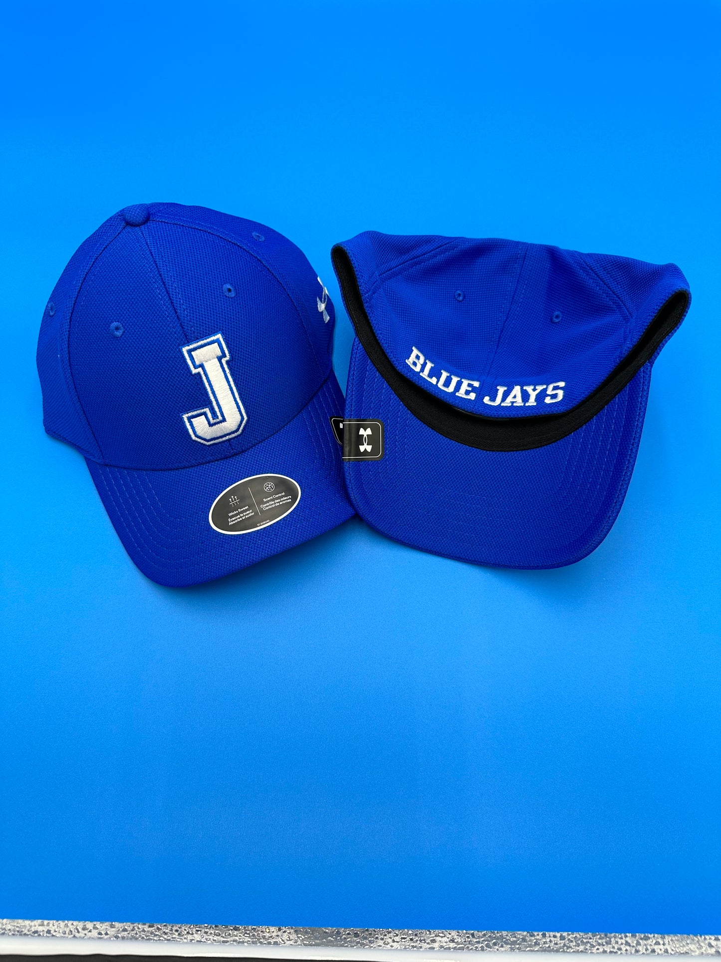 Under Armour 100% Polyester - Antimicrobial finish. Structured build w/a slightly higher crown. Stretch construction. J on front w/Blue Jays on back.