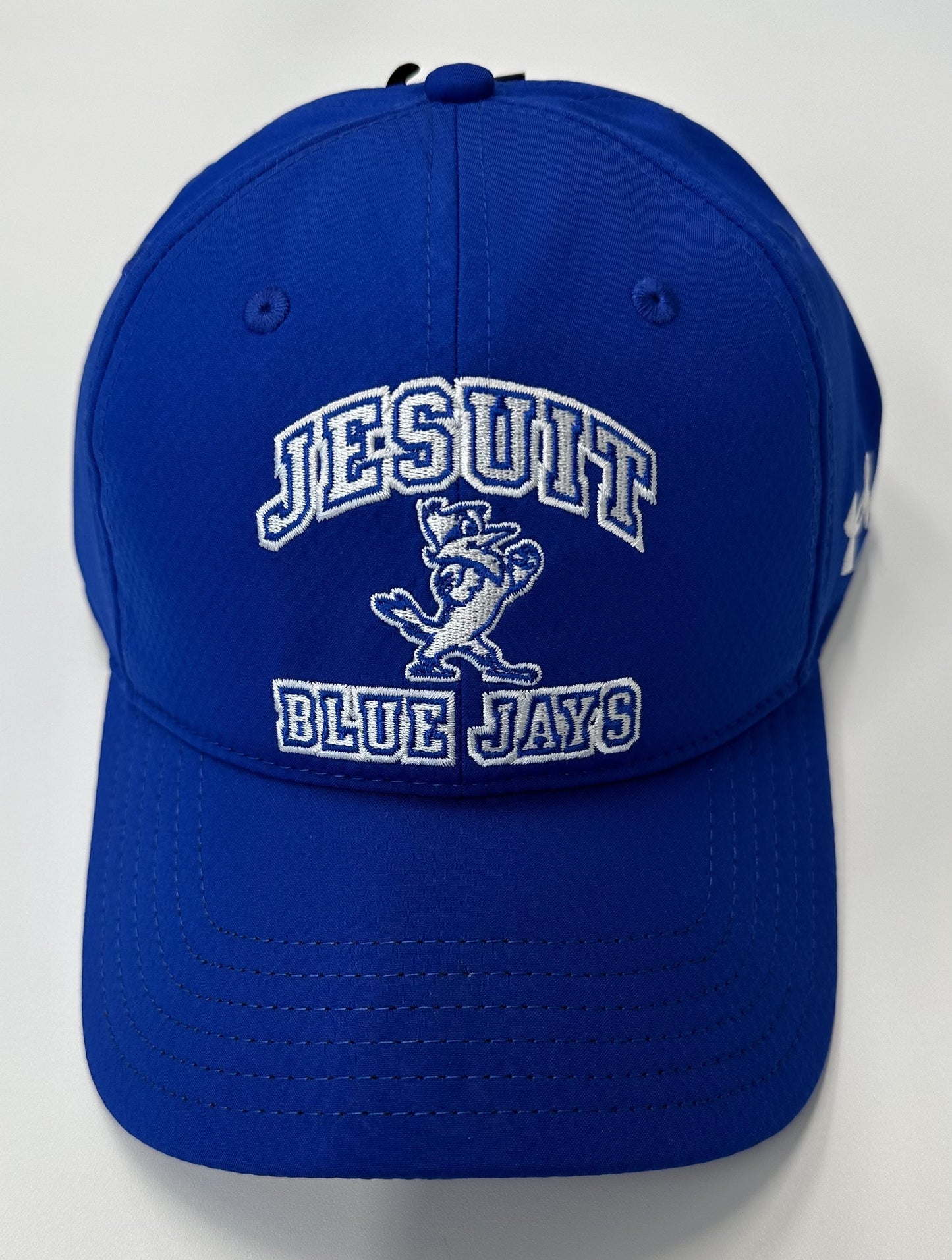 Under Armour 100% Polyester. Relaxed Unstructured fit. Curved visor. Velcro adjustable closure. One Size Fits Most. Blue w/Jesuit Blue Jays & Jayson.