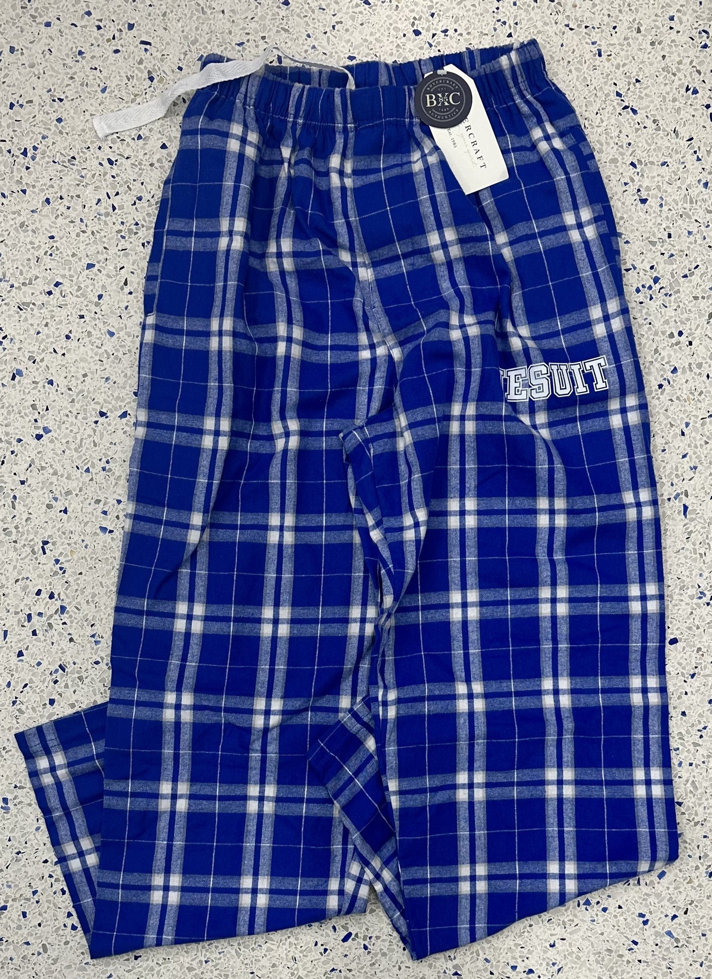 Boxercraft.  100% cotton flannel, 4.3 ounce.  Self-folded waistband (with inner drawcord), hidden button-close fly.  Also has pockets.  These flannel pants will keep you warm and comfortable with double-brushed cotton softness.  JESUIT screenprint logo.