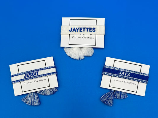 Custom Creations.  Woven bracelets w/tassel - adjustable. Royal Blue &amp; White.  Available in three styles:  JESUIT, JAYS & JAYETTES