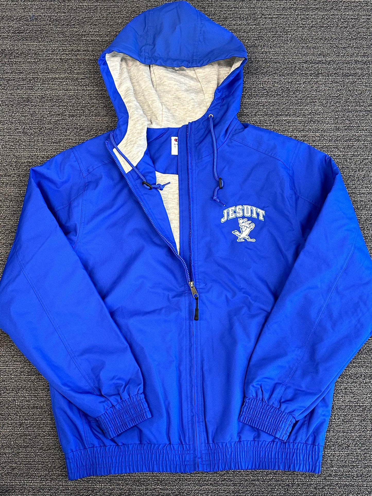 Champion.  Outer:  100% Polyester - Water Resistant.  Jersey Knit Lining:  61% Polyester/27% Cotton/12% Rayon.  Scuba collar w/hood including adjustable drawcords.  Self fabrics at waistband & cuff w/elastic to block wind.  Roll forward should, 3 piece hood & sleeve.