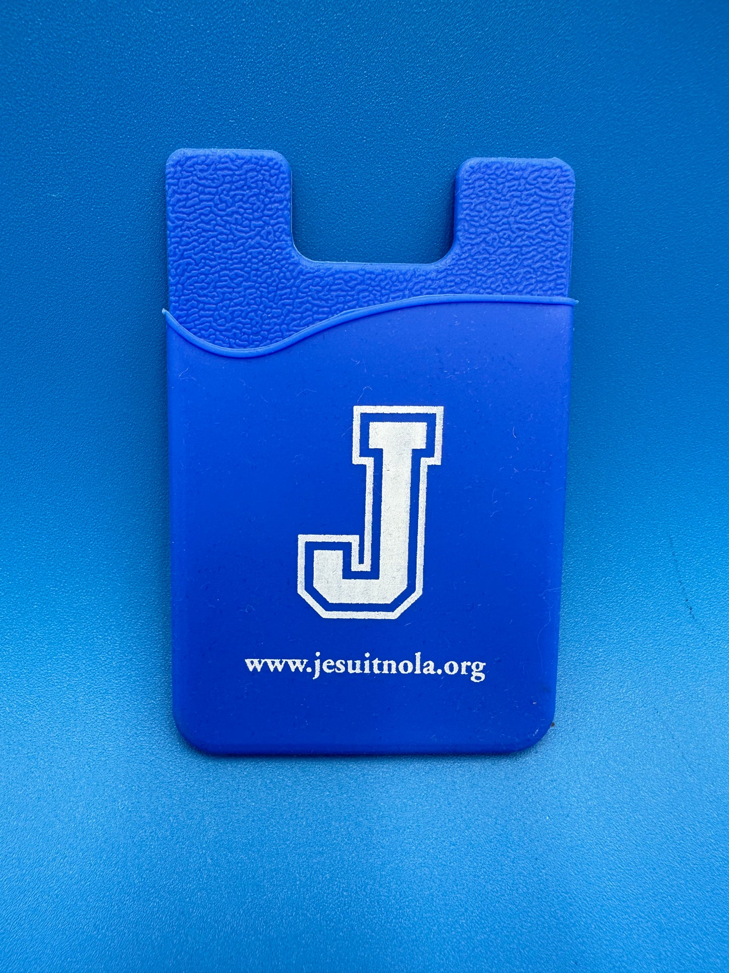 Silicone stick-on phone wallet credit card or I.D. holder with Jesuit logo.