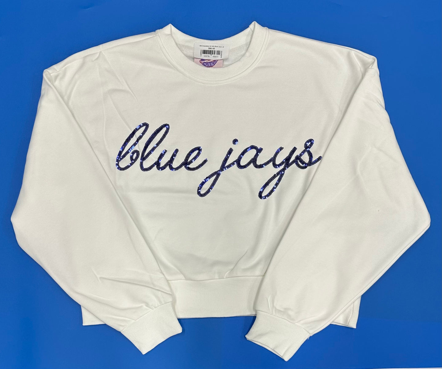 Sparkle City.

49% Cotton/51% Polyester.

Set in self collar, dropped shoulder. 1x1 rib at collar, waist and cuffs.

Shorter length, Relaxed fit.

Accented with cursive Blue Jays logo in royal blue sequins.