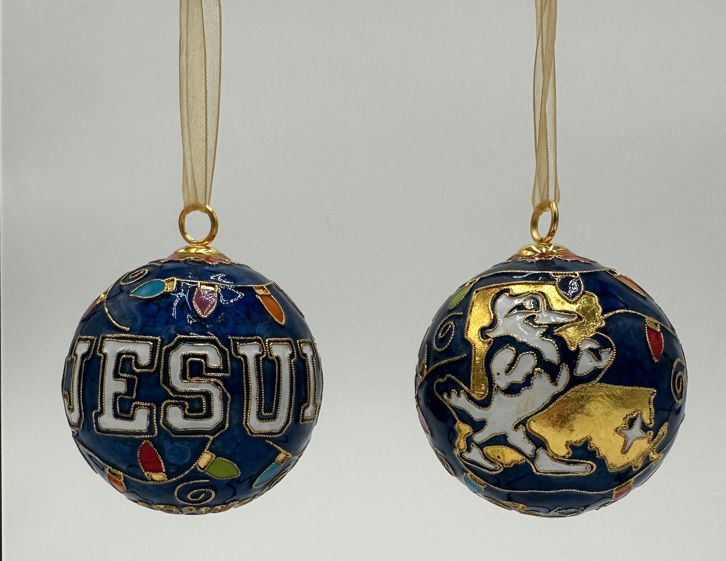 Kitty Keller Designs.

Our newest Christmas ornament to add to your collection. This year's round ornament features the JESUIT logo highlighted with festive Christmas lights and our beloved Jayson showing you exactly where we are located - NOLA!

Hand-crafted cloisonne ornaments are truly one-of-a-kind. Each gold-plated wire creating the design is formed and shaped by hand.

Comes in a silk covered gift box.