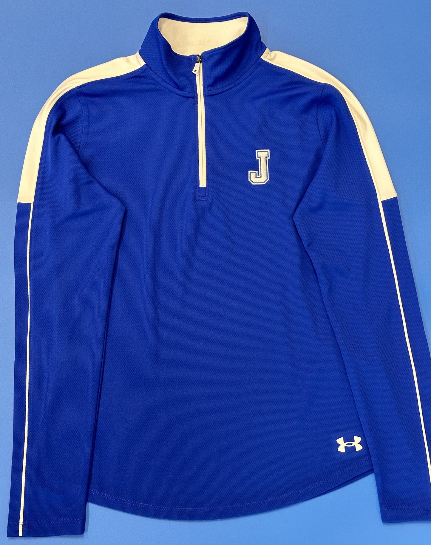 Under Armour.  100% Polyester.  Soft ant-pick, anti-pill fabric has cleaner, snag-free finish.  4-way stretch construction moves better in every direction. Material wicks sweat & dries really fast.   Embroidered J logo.